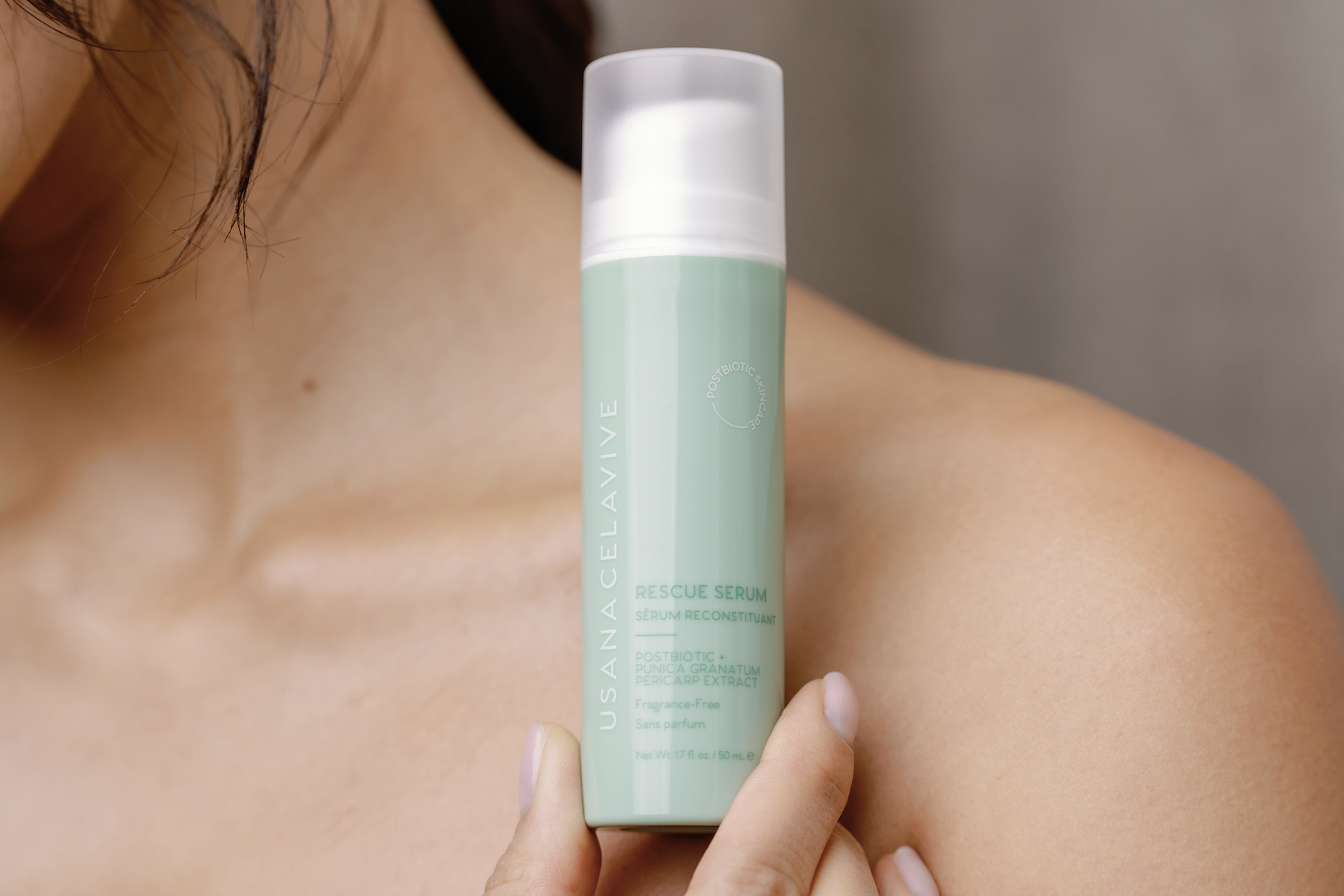 woman holding postbiotic rescue serum to her body, close crop